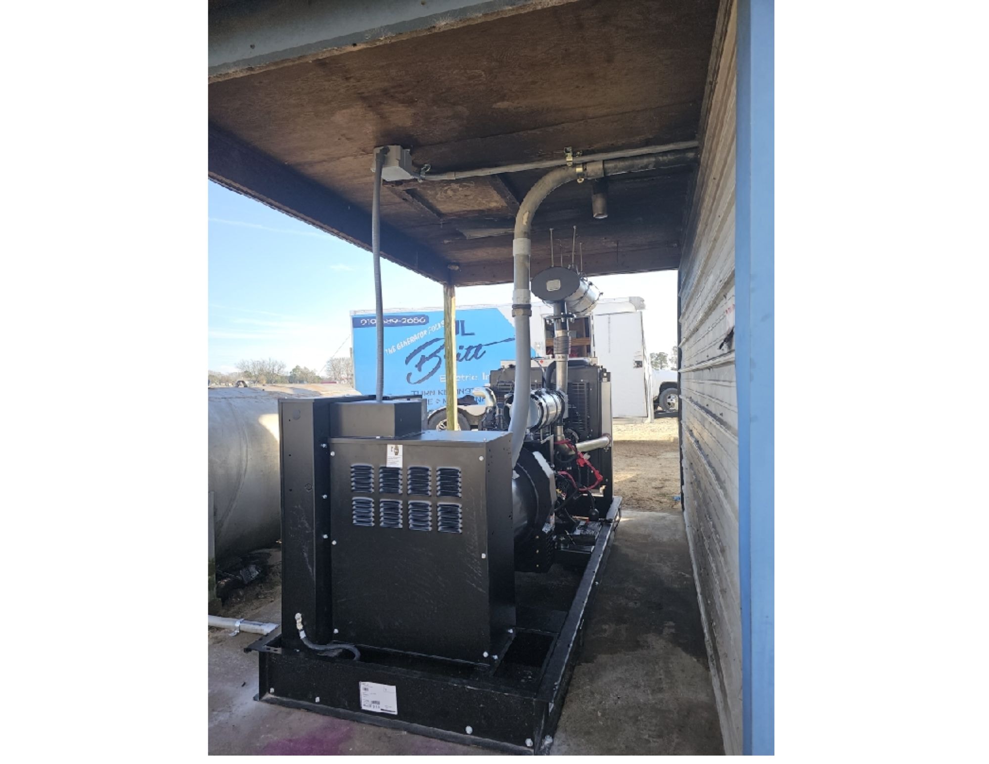 Agricultural generator installation inside a covered farm structure with JL Britt truck visible