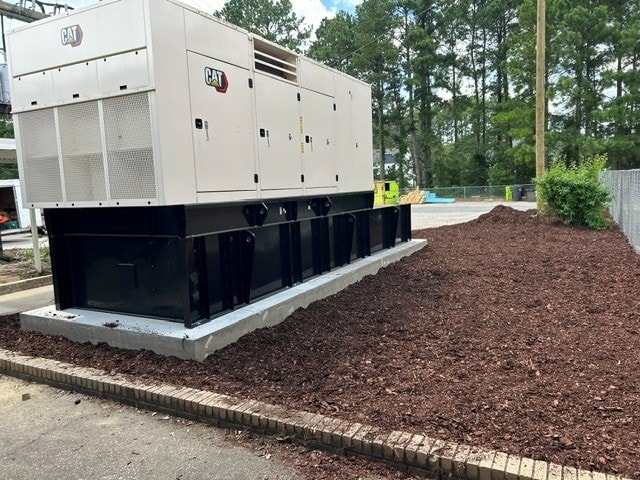 CAT generator unit installed on a raised concrete base surrounded by landscaping