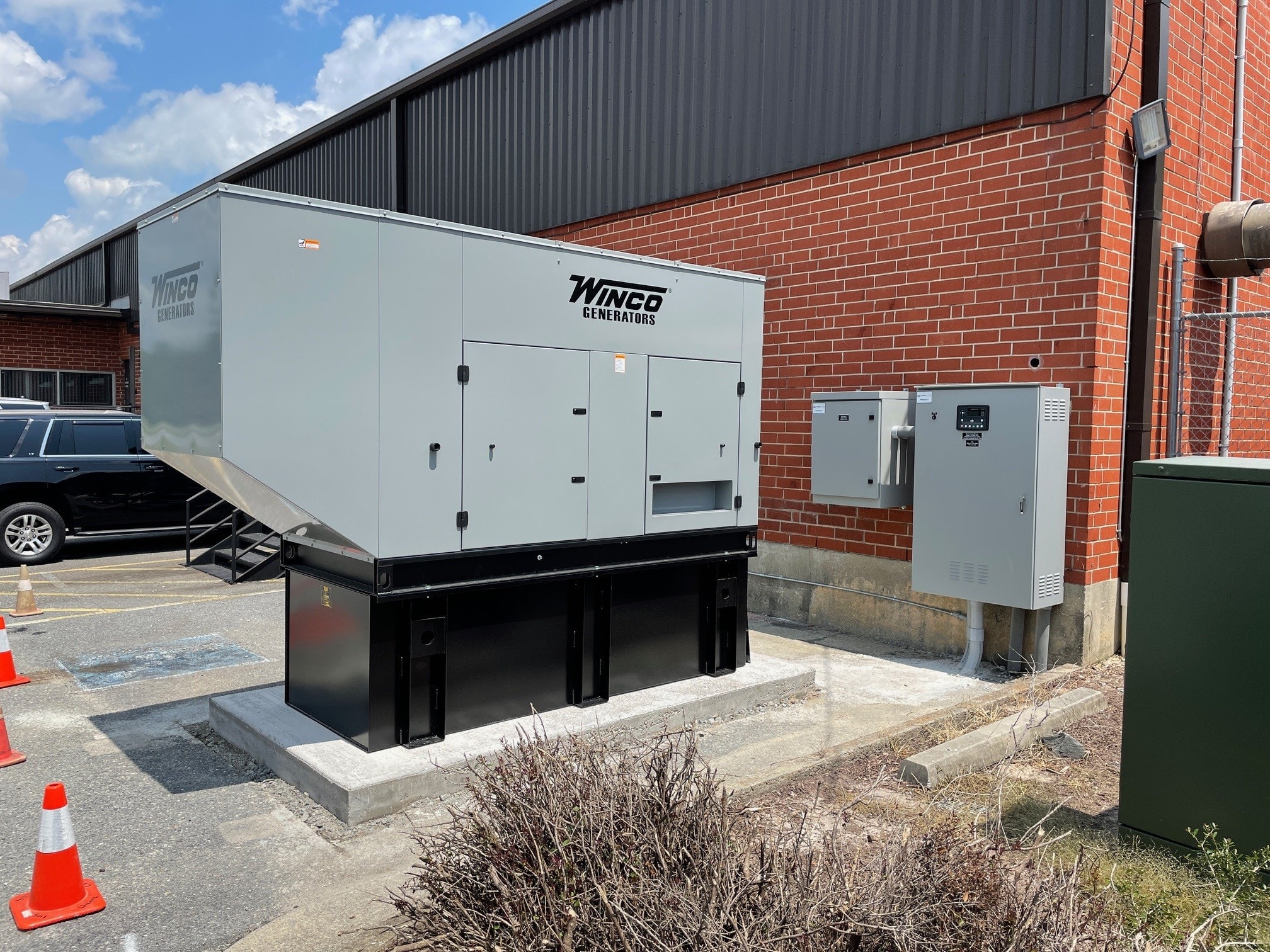 Large Winco commercial generator installed on a concrete pad outside a brick building